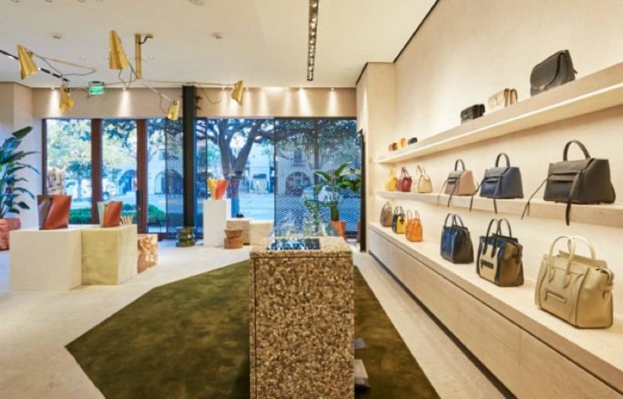 Celine boutique interior with handbags on backlit shelving and a stone plinth display