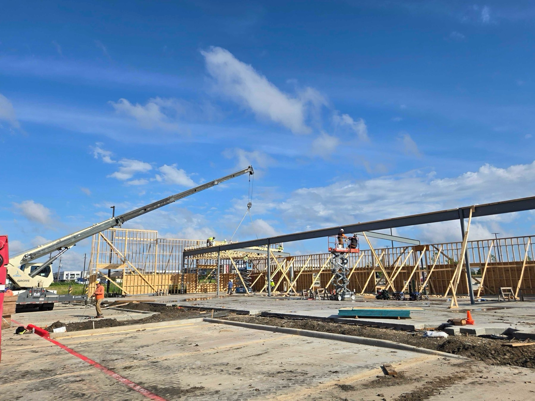Prosper Retail Shell under construction — timber framing and structural steel being set by crane over a poured slab
