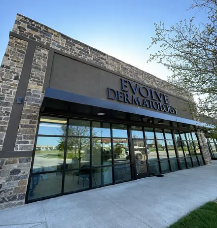 Evolve Dermatology clinic exterior in stone and glass with a full-height curtain wall